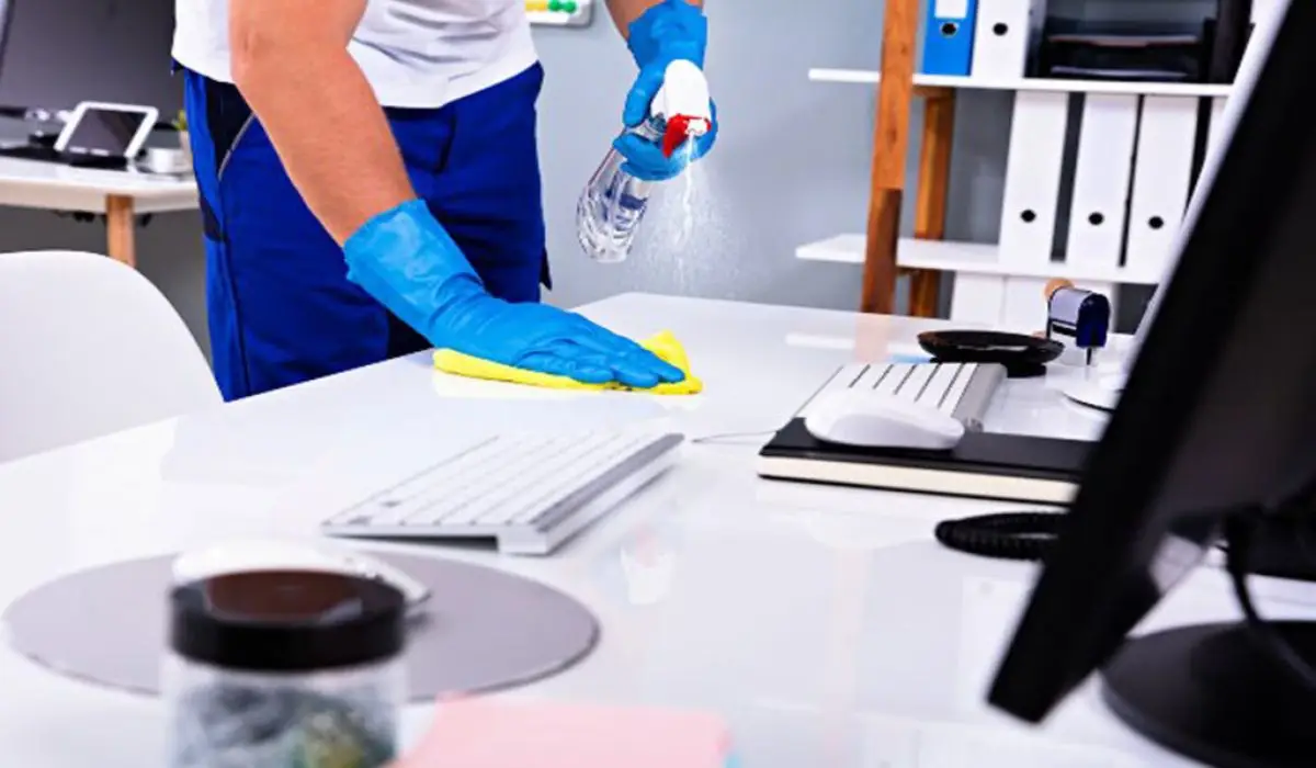 a man in blue rubber gloves wiping the desk