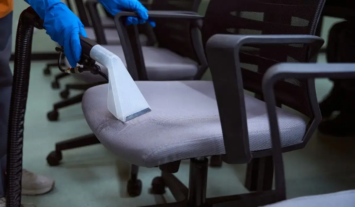 Technician deep cleaning an office chair with professional upholstery extraction equipment as part of a commercial office cleaning checklist.